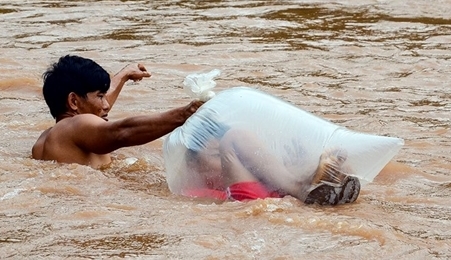 奠边省学生们躲在塑料袋里渡过洪水上学