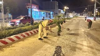 Công an cùng người dân thu dọn đá dăm rơi vãi trên mặt đường lộ