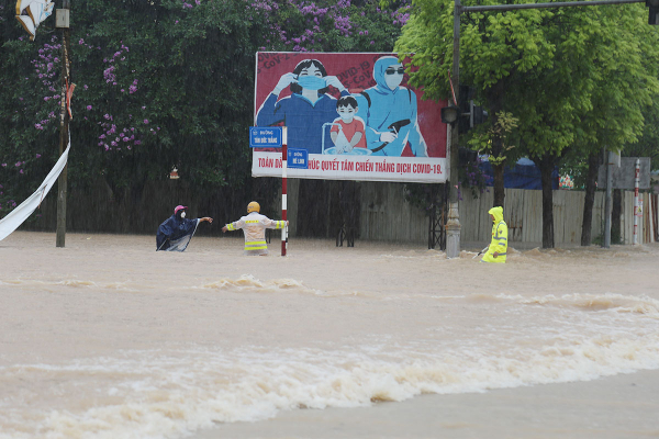 Hỗ trợ người dân đi qua các đoạn đường bị ngập úng sau trận mưa lớn -0
