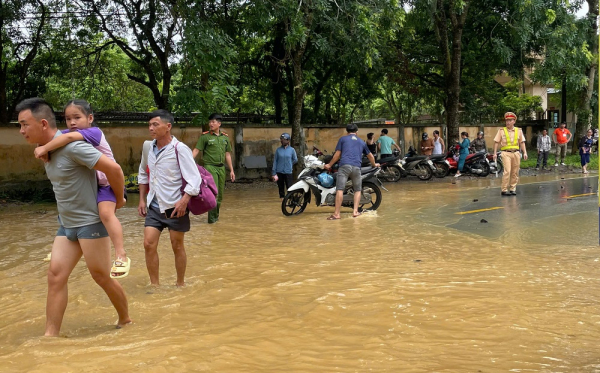 Công an huyện Bảo Thắng giúp dân di chuyển qua đoạn đường bị ngập do mưa lớn -0