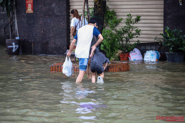Đường phố Hà Nội vẫn ngập sâu sau mưa lớn, người dân dắt xe máy qua biển nước -6