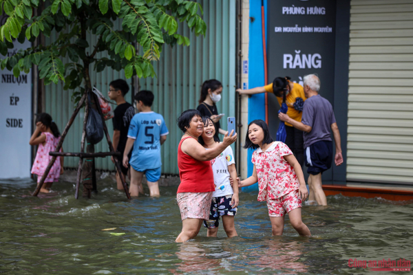 Đường phố Hà Nội vẫn ngập sâu sau mưa lớn, người dân dắt xe máy qua biển nước -7