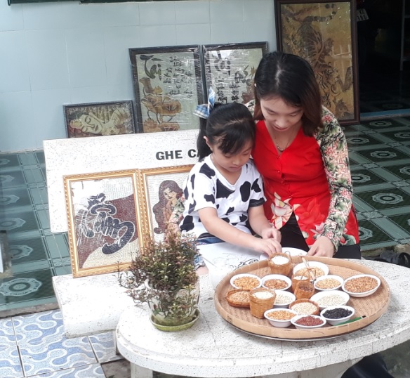 chị tuyết phượng hướng dẫn bé lâm yến nhi sáng tác tranh gạo. (ảnh trương anh sáng).jpg -0