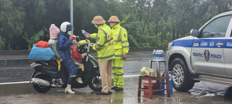 CSGT đội mưa tiếp đồ ăn, thức uống cho người dân trở lại miền Nam làm việc sau Tết -0