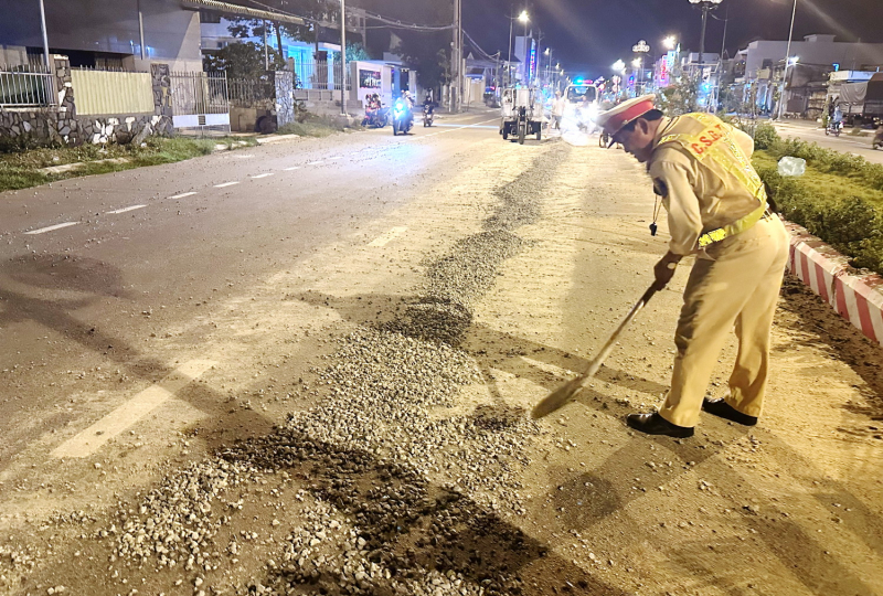 Công an cùng người dân thu dọn đá dăm rơi vãi trên mặt đường lộ -0