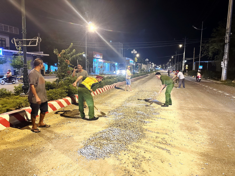 Công an cùng người dân thu dọn đá dăm rơi vãi trên mặt đường lộ -0